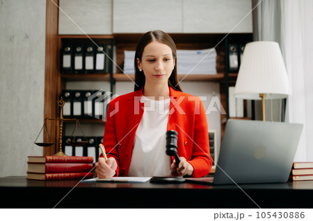 justice and law concept. Female judge in a courtroom the gavel, working with smart phone and laptop and digital tablet computer on black table justice and law concept. Female judge in a courtroom the gavel, working with smart phone and laptop and digital tablet computer on black table 105430886