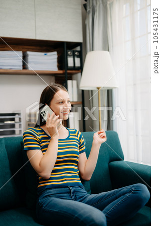 Confident Caucasian woman with a smile standing holding notepad and tablet in living room on the sofa at office Confident Caucasian woman with a smile standing holding notepad and tablet in living room on the sofa at office 105431175