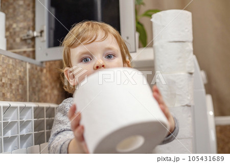 A cute boy is holding toilet paper roll in bathroom. Young boy with toilet paper 105431689