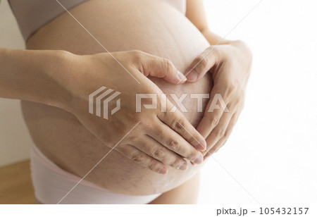 妊娠線と正中線があるお腹に手をあてる臨月の女性 妊娠線と正中線があるお腹に手をあてる臨月の女性 105432157