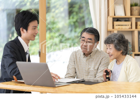 訪問営業と話しをするシニア夫婦 105433144