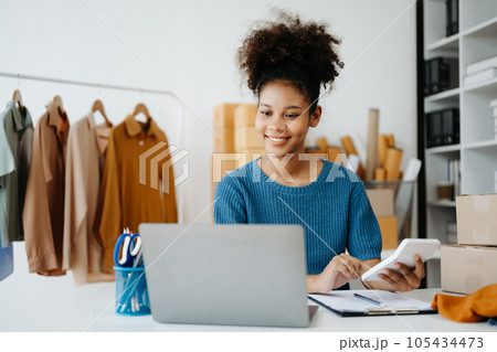 Young African woman running online store Startup small business SME, using smartphone or tablet taking receive and checking online purchase shopping order in office Young African woman running online store Startup small business SME, using smartphone or tablet taking receive and checking online purchase shopping order in office 105434473
