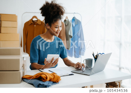 Young African woman running online store Startup small business SME, using smartphone or tablet taking receive and checking online purchase shopping order in office Young African woman running online store Startup small business SME, using smartphone or tablet taking receive and checking online purchase shopping order in office 105434536