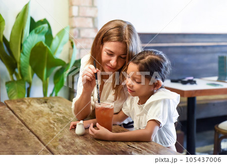 Little girl and her mother drinking ice tea together in a cafe Little girl and her mother drinking ice tea together in a cafe 105437006
