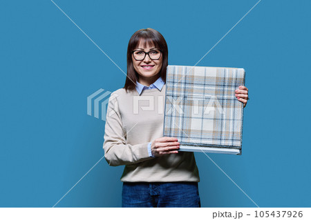 Woman with samples of fabrics for curtains and upholstery on blue background Woman with samples of fabrics for curtains and upholstery on blue background 105437926