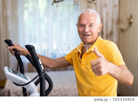 Mature man exercising on an elliptical machine and showing thumb up 105439954