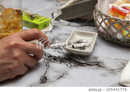 スナックのカウンターでタバコを吸う男性の手元 105441770