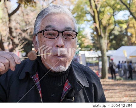 An asian man in glasses eating dango 105442894