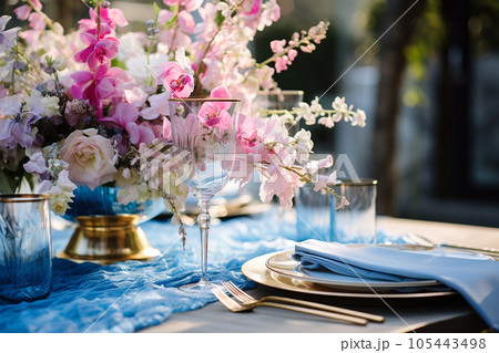 Flower table decorations for wedding dinner. Wedding table set for holiday, event, party, wedding reception in outdoor restaurant. Pink and blue with gold wedding table setting. AI generated 105443498