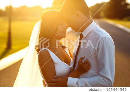 Lovely wedding couple at sunset. Bride, groom in wedding attire with bouquet of flowers. Romantic. 105444545