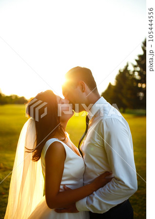 Lovely wedding couple at sunset. Bride, groom in wedding attire with bouquet of flowers. Romantic. 105444556