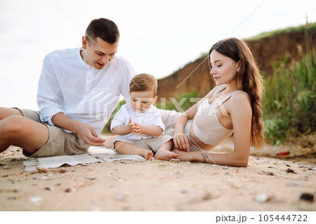 Cheerful young family with little baby boy spending time together on the beach. 105444722