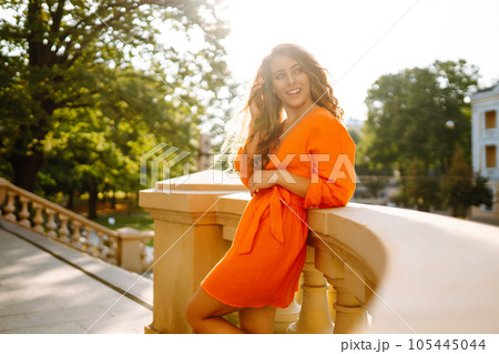 Female tourist in bright dress enjoys sights of the city on sunny day. Concept of lifestyle, fashion 105445044