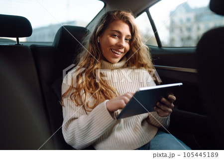 Woman sitting in back seat of car with tablet in hand. Business, taxi, technologie, online concert. 105445189
