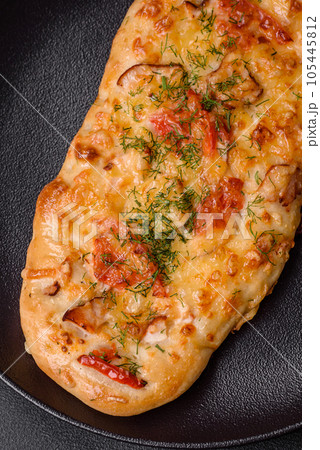 Delicious oven fresh flatbread pizza with cheese, tomatoes, sausage, salt and spices 105445812