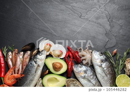 Fresh fish and different seafood on black table, flat lay. Space for text Fresh fish and different seafood on black table, flat lay. Space for text 105446282