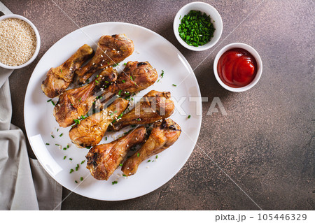 Spicy baked chicken drumsticks with green onions and sesame seeds on a plate top view Spicy baked chicken drumsticks with green onions and sesame seeds on a plate top view 105446329