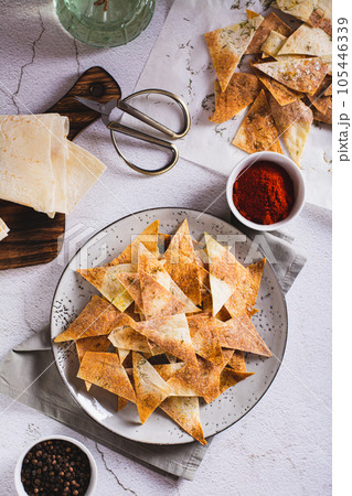Spicy chips with paprika and dill from tortilla on a plate top and vertical view 105446339