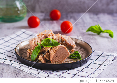 Pieces of canned tuna and basil leaves on a plate 105446374