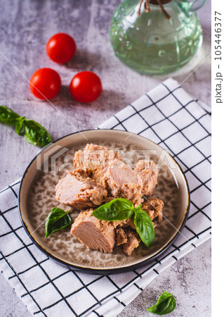 Canned tuna fish meat and basil on a plate on the table vertical view 105446377