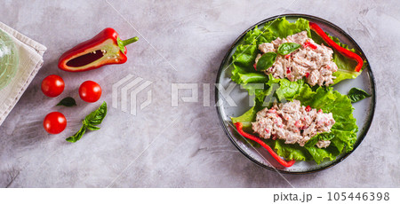Canned tuna salad with pepper and egg on lettuce leaves on a plate top view web banner 105446398