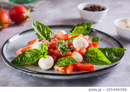 Caprese salad with tomatoes, mozzarella, basil and olive oil on a plate Caprese salad with tomatoes, mozzarella, basil and olive oil on a plate 105446399