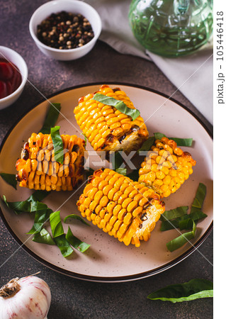 Grilled corn with spices, butter and garlic on a plate on the table vertical view 105446418
