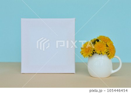 Dandelion bouquet in a vase and picture frame on a blue background. 105446454