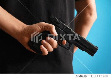 Man holding gun on blue background, closeup Man holding gun on blue background, closeup 105446586