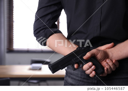 Man holding gun indoors, closeup. Dangerous criminal 105446587