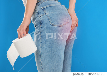 Woman with toilet paper suffering from hemorrhoid on light blue background, closeup 105446828