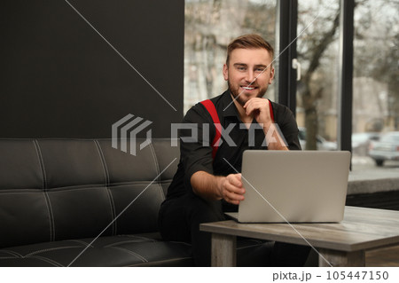 Young business owner with laptop on couch indoors 105447150