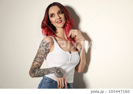 Beautiful woman with tattoos on arms against light background 105447160