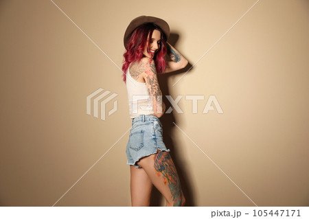 Beautiful woman with tattoos on body against beige background Beautiful woman with tattoos on body against beige background 105447171