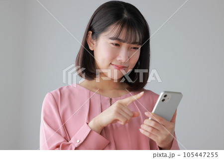 スマホを操作するカジュアルな服装の女性_1 スマホを操作するカジュアルな服装の女性_1 105447255