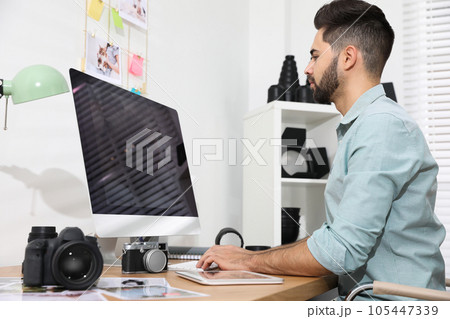 Professional photographer working at table in office Professional photographer working at table in office 105447339