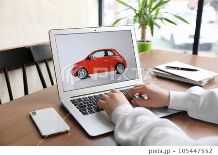 Woman using laptop to buy car at wooden table indoors, closeup 105447552