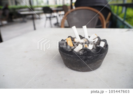 Close up burning cigarette in ashtray on table Close up burning cigarette in ashtray on table 105447603