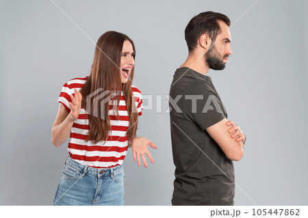 Woman shouting at her boyfriend on grey background. Relationship problems Woman shouting at her boyfriend on grey background. Relationship problems 105447862