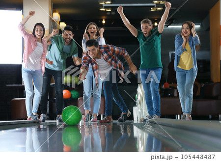 Man throwing ball and spending time with friends in bowling club 105448487