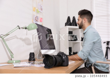 Professional photographer working at table in office, focus on camera 105448493