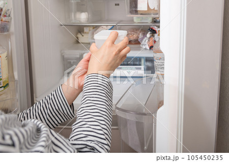 【冷蔵室からタッパを取り出す主婦】 105450235