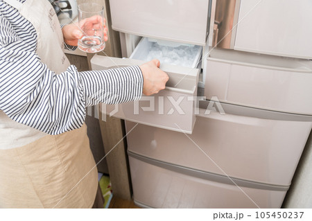 【製氷室から氷をグラスに入れる主婦】 105450237