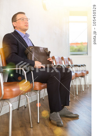 Adult man with glasses sitting in line at reception Adult man with glasses sitting in line at reception 105450529