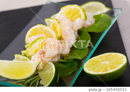 Seafood ceviche from hake on a glass plate with lime and greens 105450531
