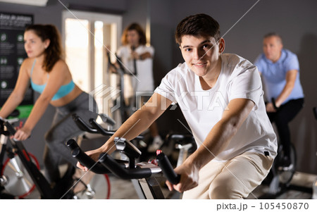 People in activewear warming up on training using exercise bike in gym 105450870