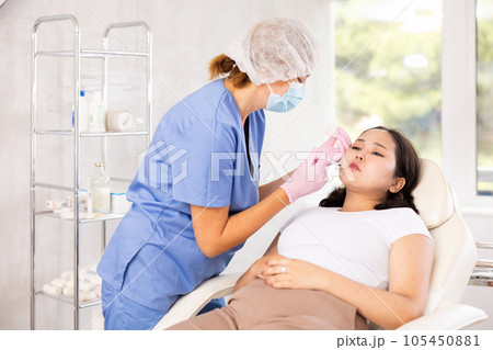 Middle-aged doctor giving injection in face Middle-aged doctor giving injection in face 105450881