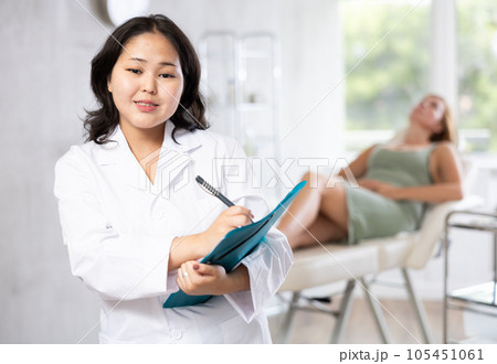 Asian professional cosmetologist advertising facial procedure to patients 105451061