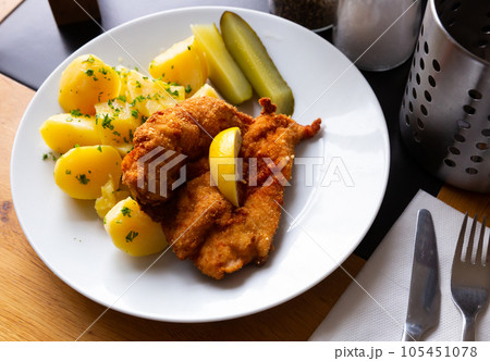 Chicken cutlet breaded with Parmesan with boiled potatoes, pickles 105451078