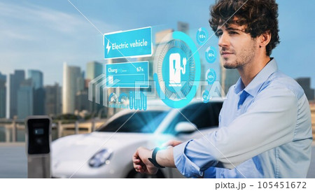 Businessman checking EV car battery status in hologram from smartwactch. Peruse Businessman checking EV car battery status in hologram from smartwactch. Peruse 105451672